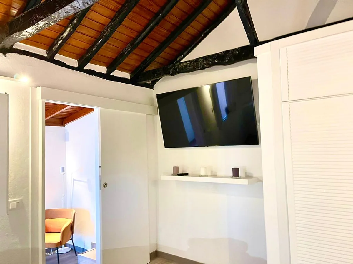 Salón del apartamento con techo de madera y televisor